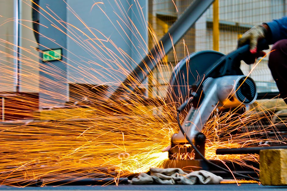 pexels-photo-1145434-1145434 A worker operates a grinder cutting metal, creating a vibrant display of sparks in an industrial setting.