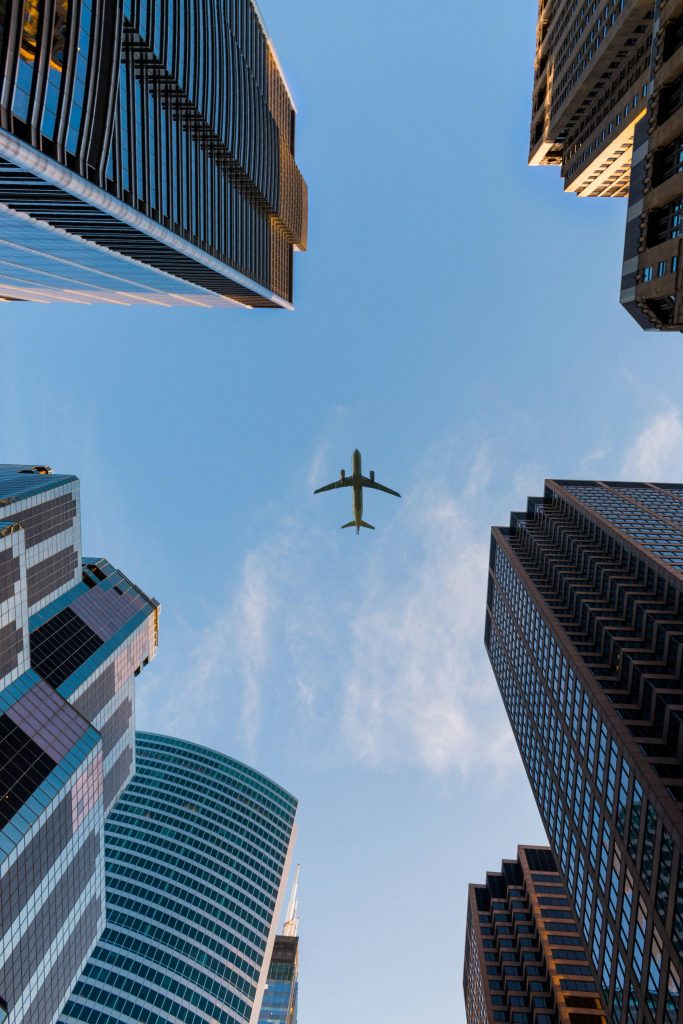 pexels-photo-1157255-1157255 Airplane flies over Chicago's modern skyscrapers against a clear sky, highlighting urban architecture.
