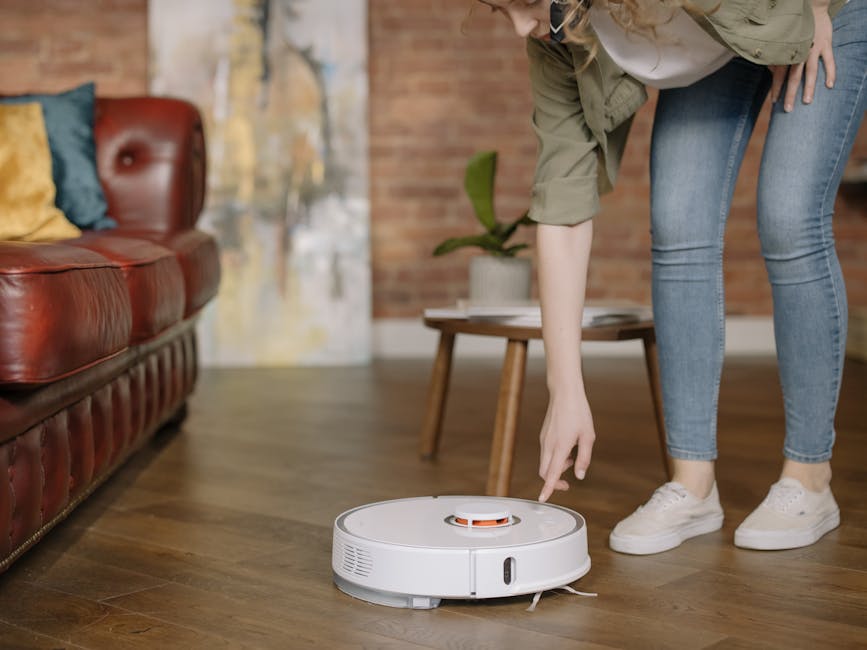 pexels-photo-4107249-4107249 A woman in jeans interacts with a robotic vacuum cleaner in a cozy, stylish living room.