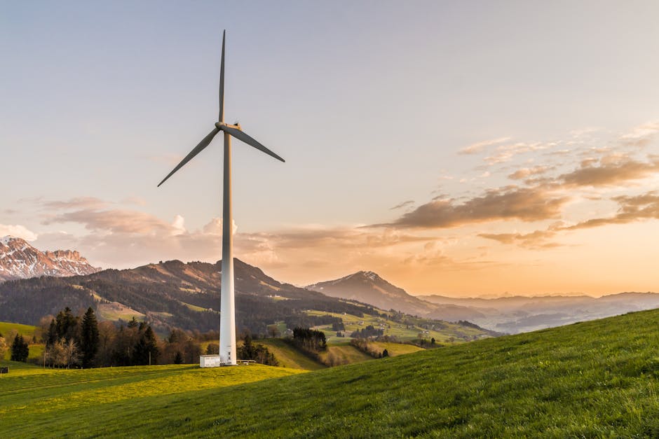 pexels-photo-414837-414837 Wind turbine amid rolling hills and mountains at sunset, symbolizing renewable energy and sustainability.